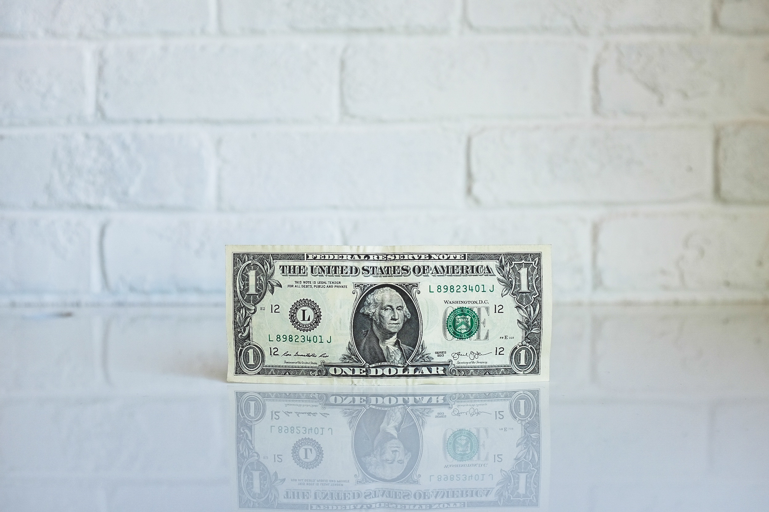 us dollar bill on white counter, white brick background